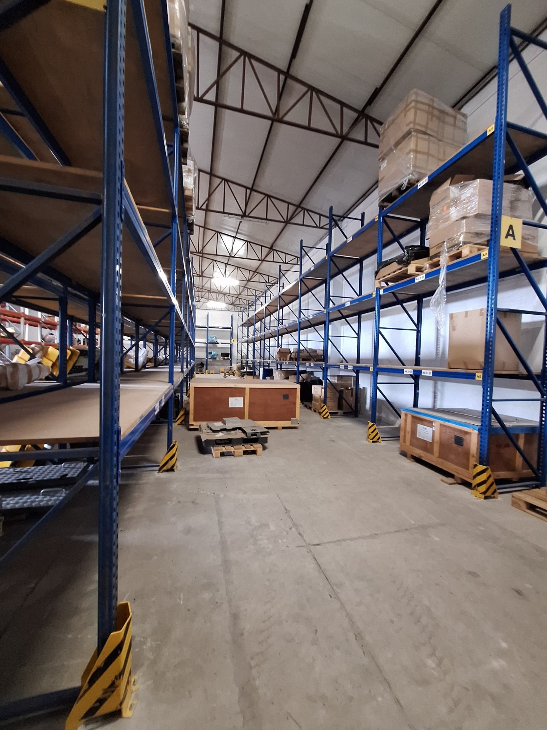 Blue industrial racking corridor with labeled bins organised by part family