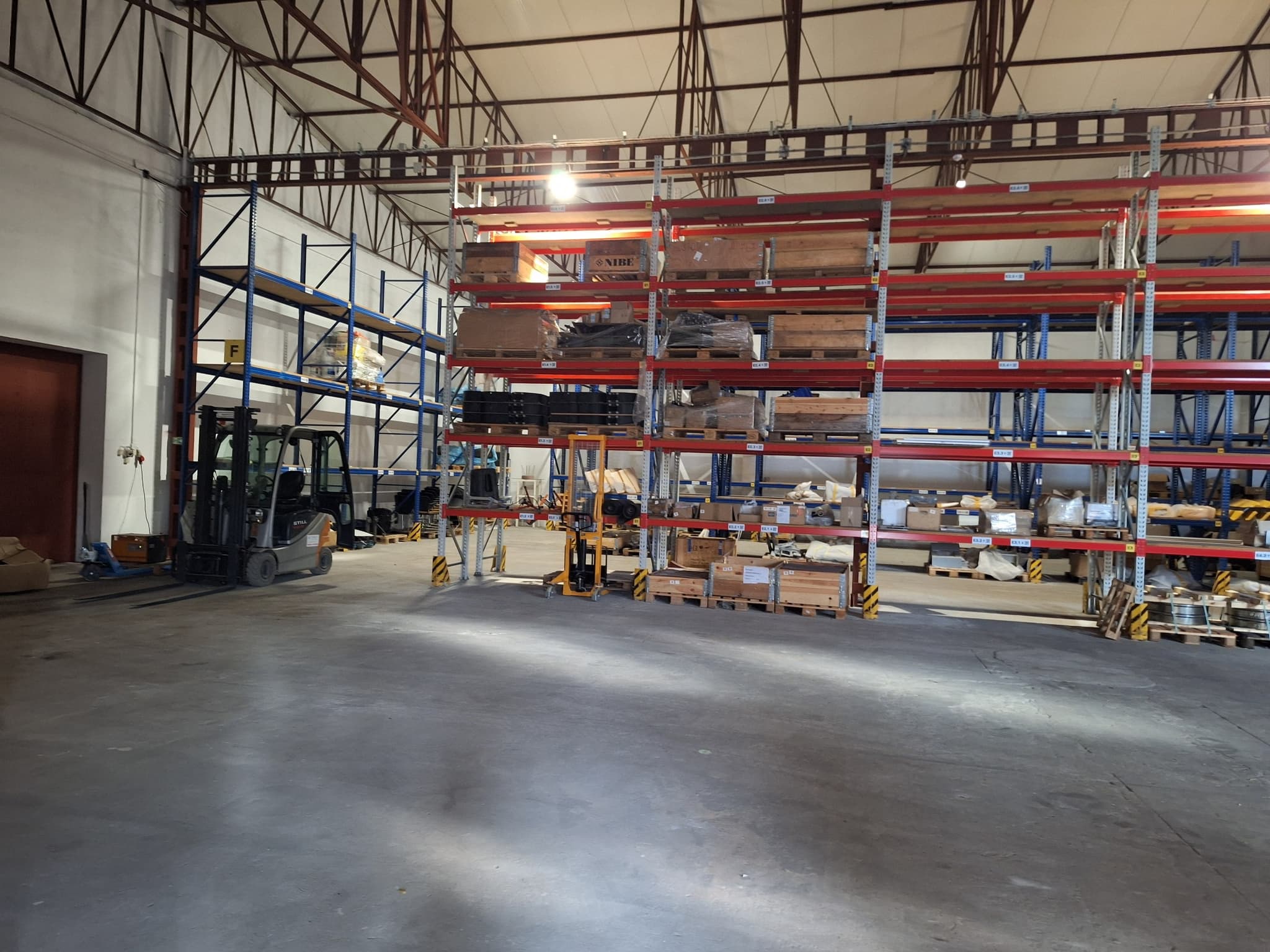 Forklift positioning a heavy pallet of rail components in a high-bay racking system